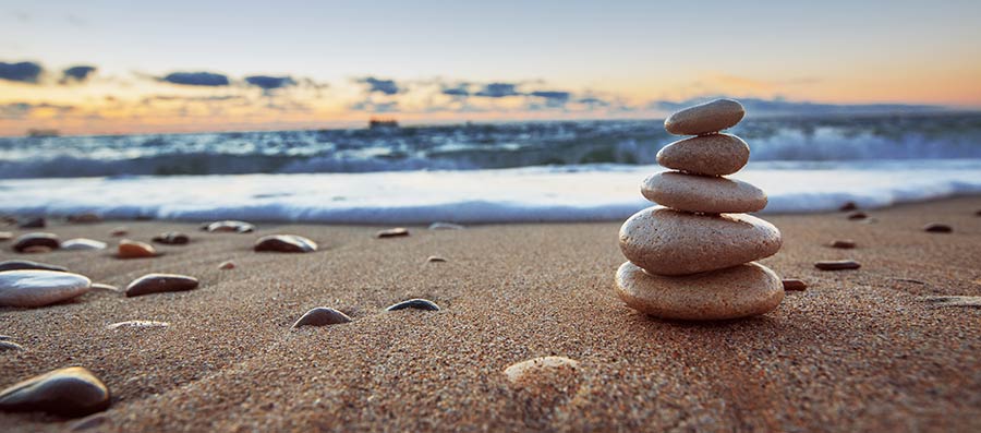 Stacked stones on a beach at sunset