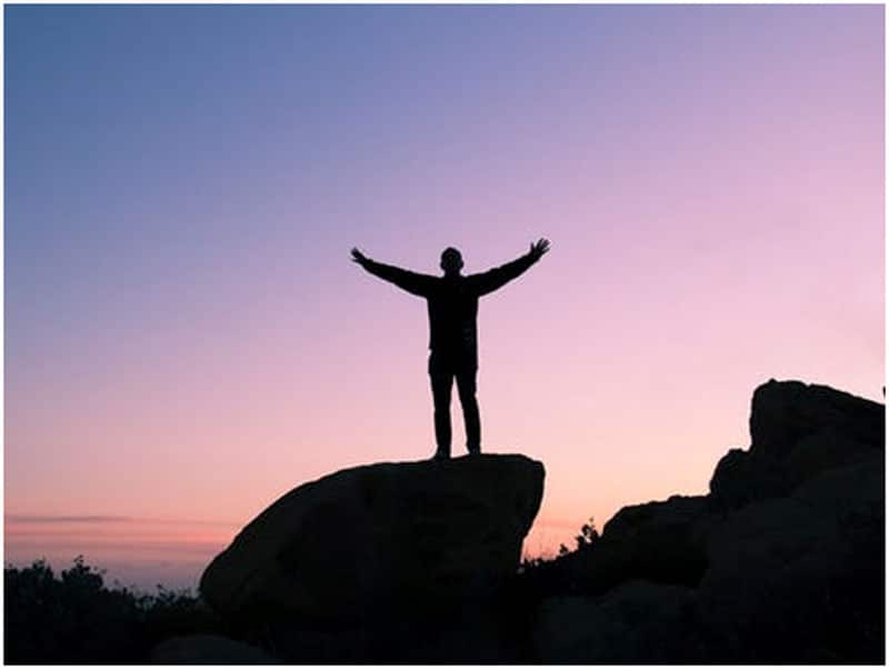 Silhouette image of a man standing on a rock in front of a sunset