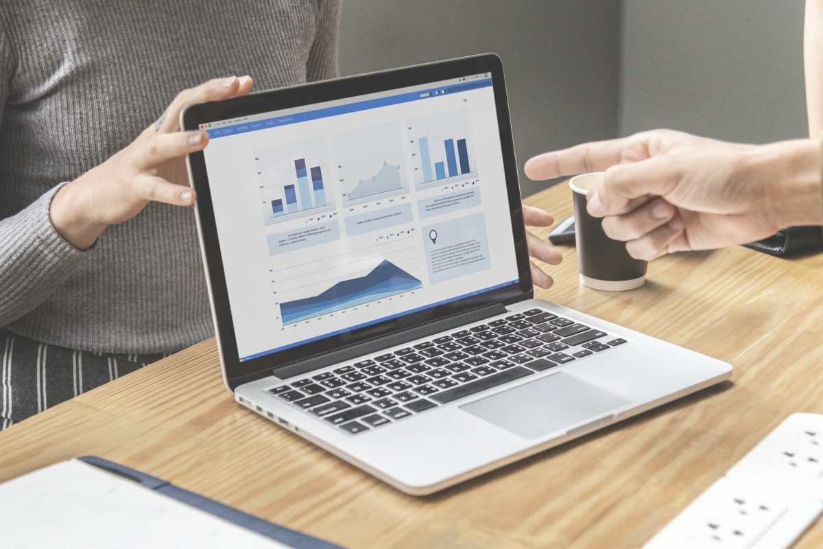 Two people reviewing investment charts on a laptop