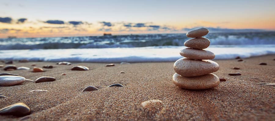 Balanced stones stacked on a beach at sunset
