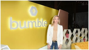 Woman standing in front of a Bumble display wall at a branded company event